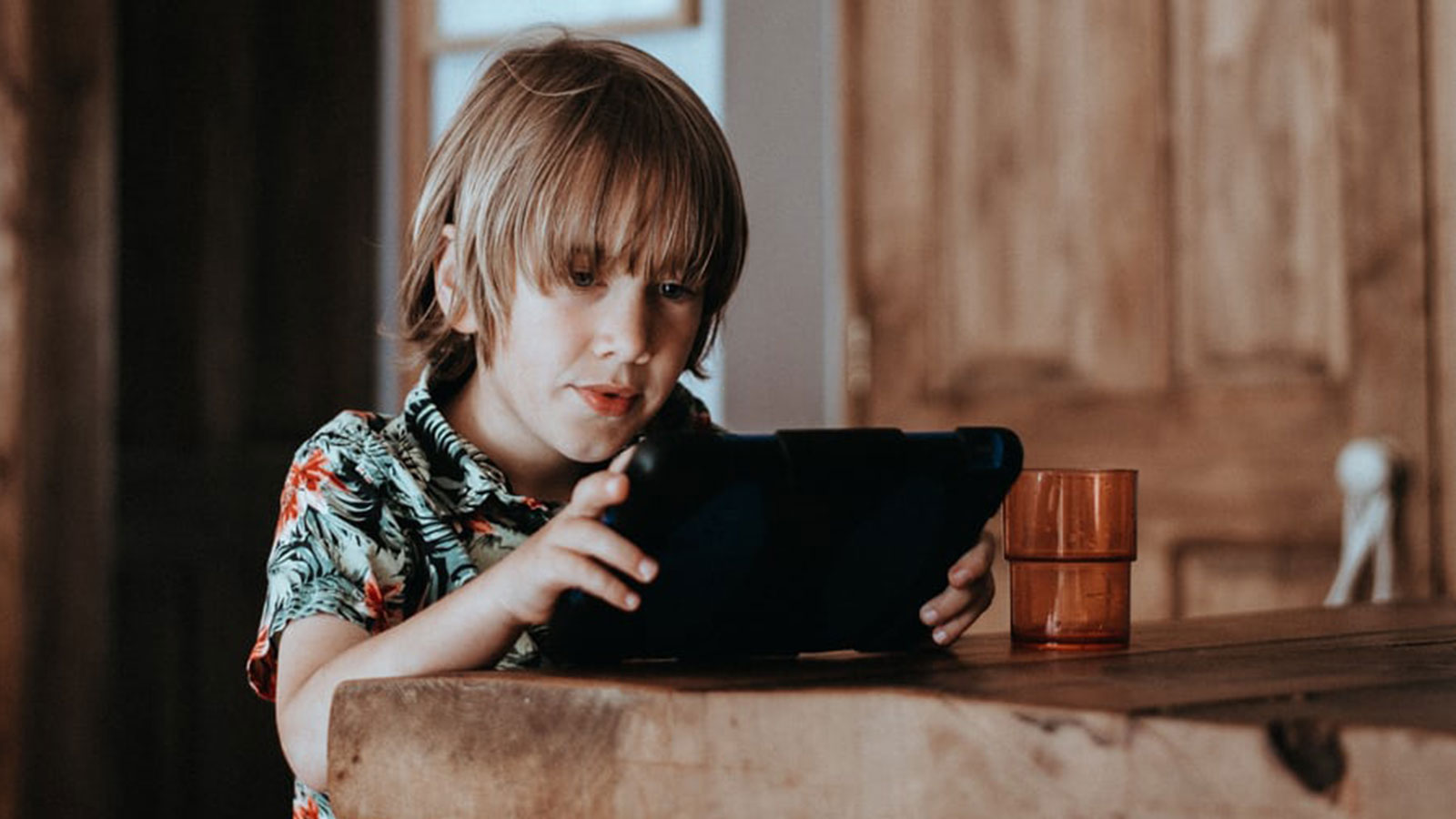 Improvisation with online therapy Thought Piece. A photo of a boy at a table looking at an iPad
