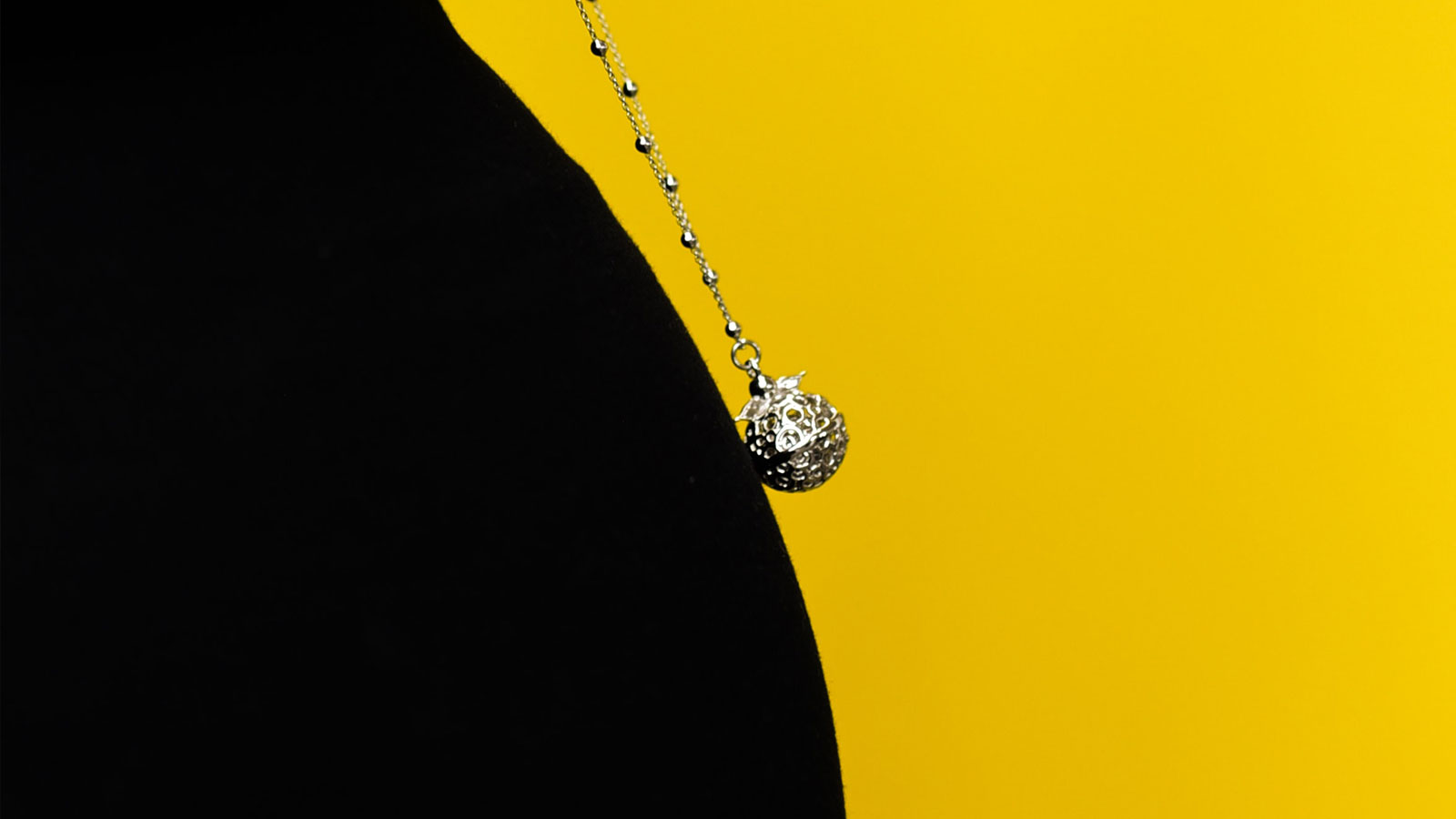 Pregnant women Thought Piece. A close up silhouette image of a pregnant belly with a necklace highlighted on a bright yellow background