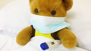 COVID, children and anxiety Thought Piece. A photo of a teddy wearing a mask holding a thermometer