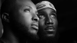 Families of colour Thought Piece featured image. Close up of two young men looking up in thought with dramatic lighting