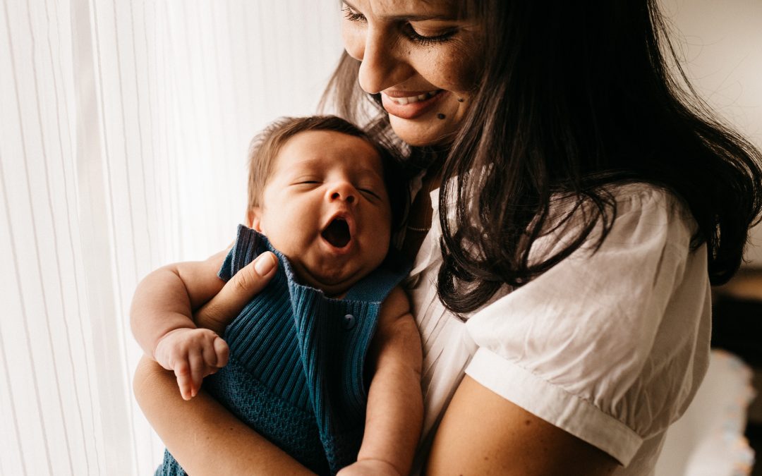 A photo of a baby yawning on mothers chest