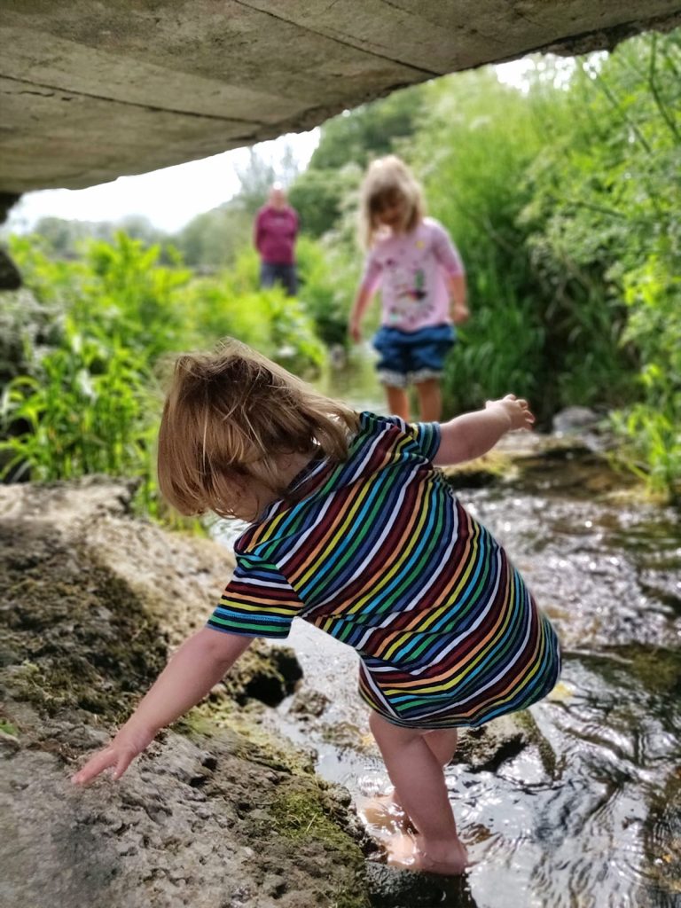 A photo of some young children playing under a bridge