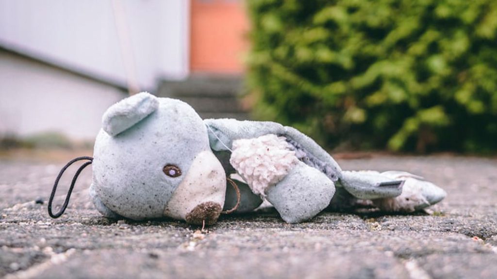A picture of a teddy on the floor outside a building