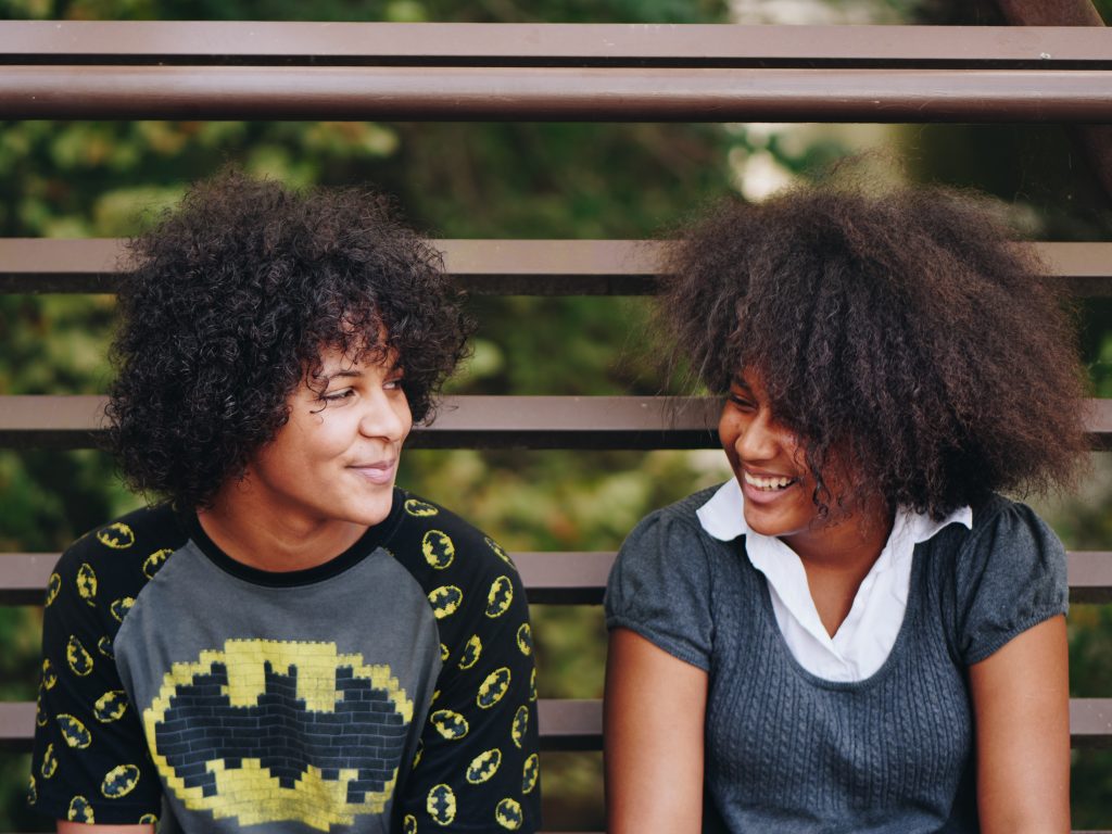 A photo of two young people on bench smiling at each other