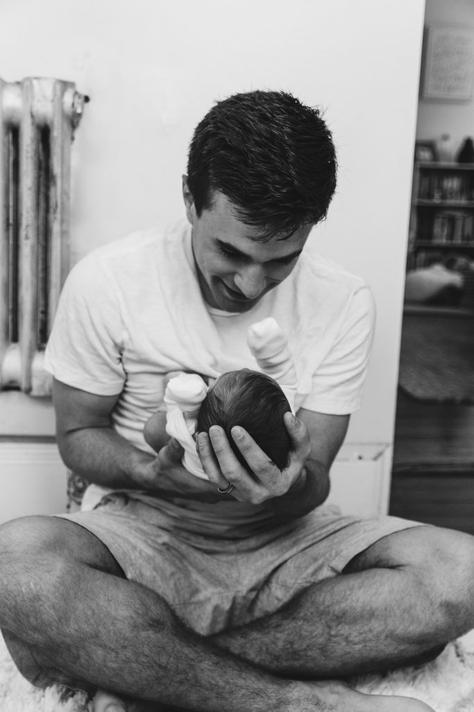A photo of a man looking at a baby cradling in his hands